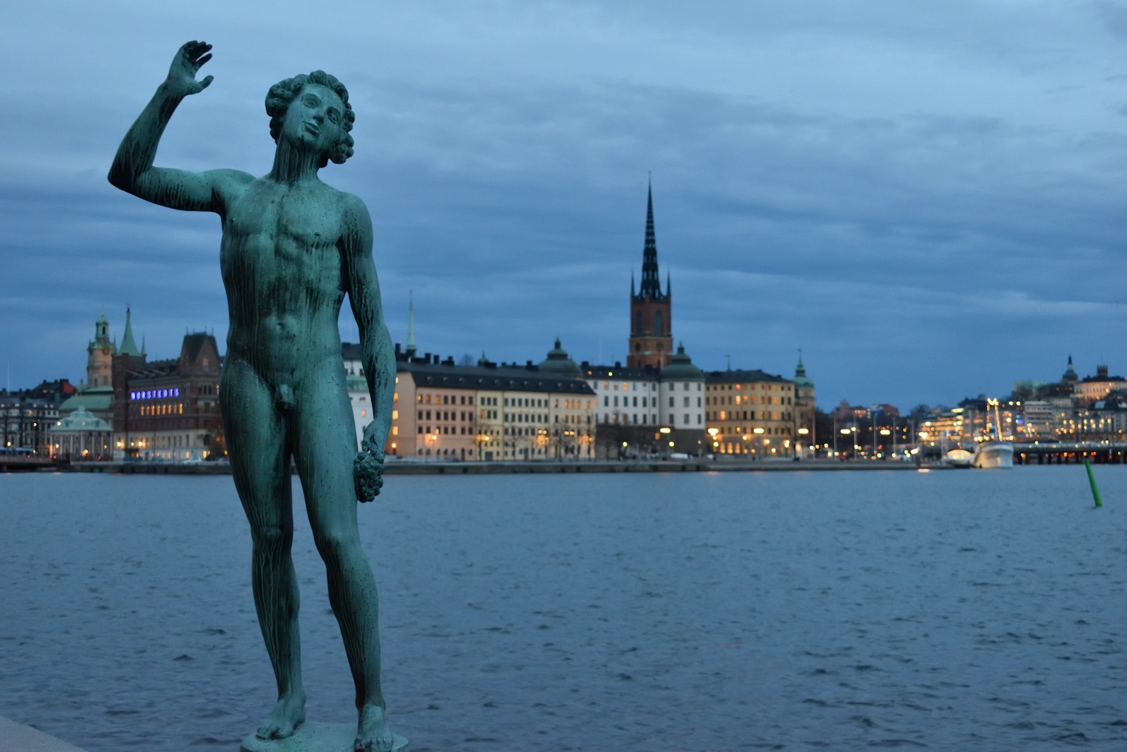 statue of man near body of water during daytime