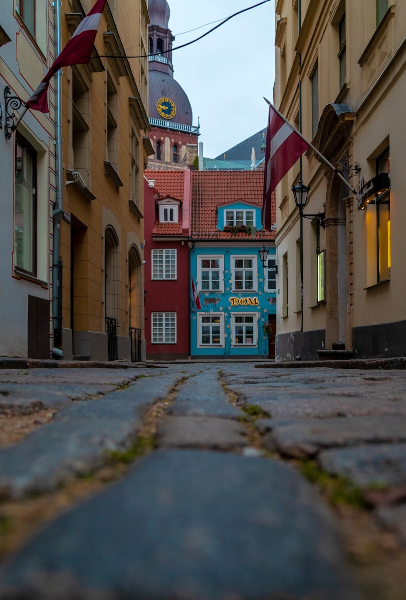 a cobblestone street with buildings and a clock tower in the background